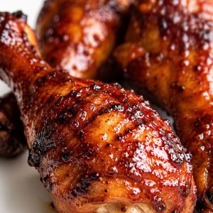 Close-up of BBQ chicken drumsticks with crispy caramelized skin and glossy homemade BBQ sauce glaze