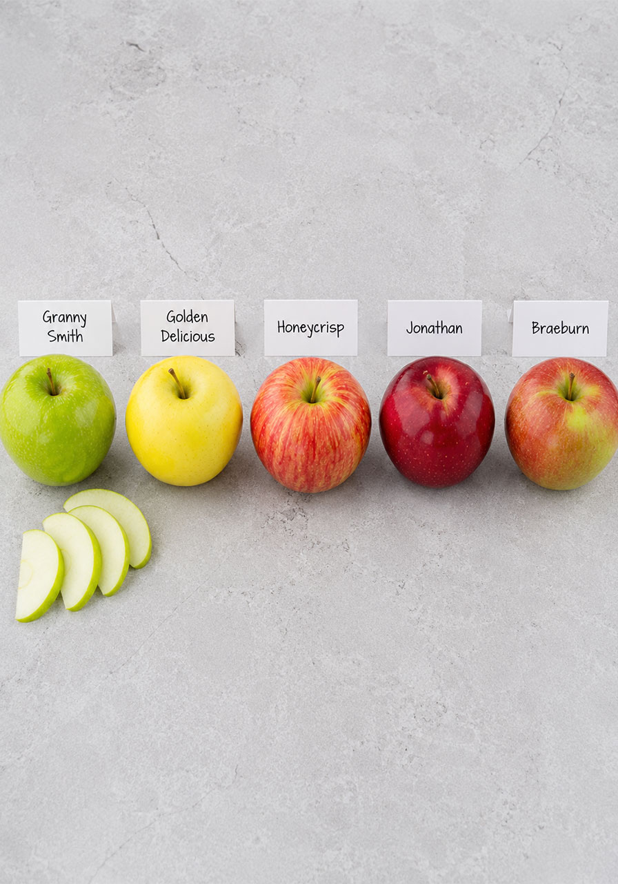 Five apple varieties including Granny Smith, Honeycrisp, and Golden Delicious shown side by side for making campfire apple pie packets