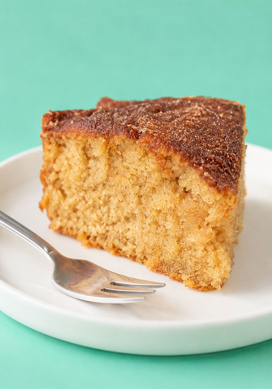Close-up slice of the best cinnamon tea cake showing buttery crumb and cinnamon sugar crust on a white plate