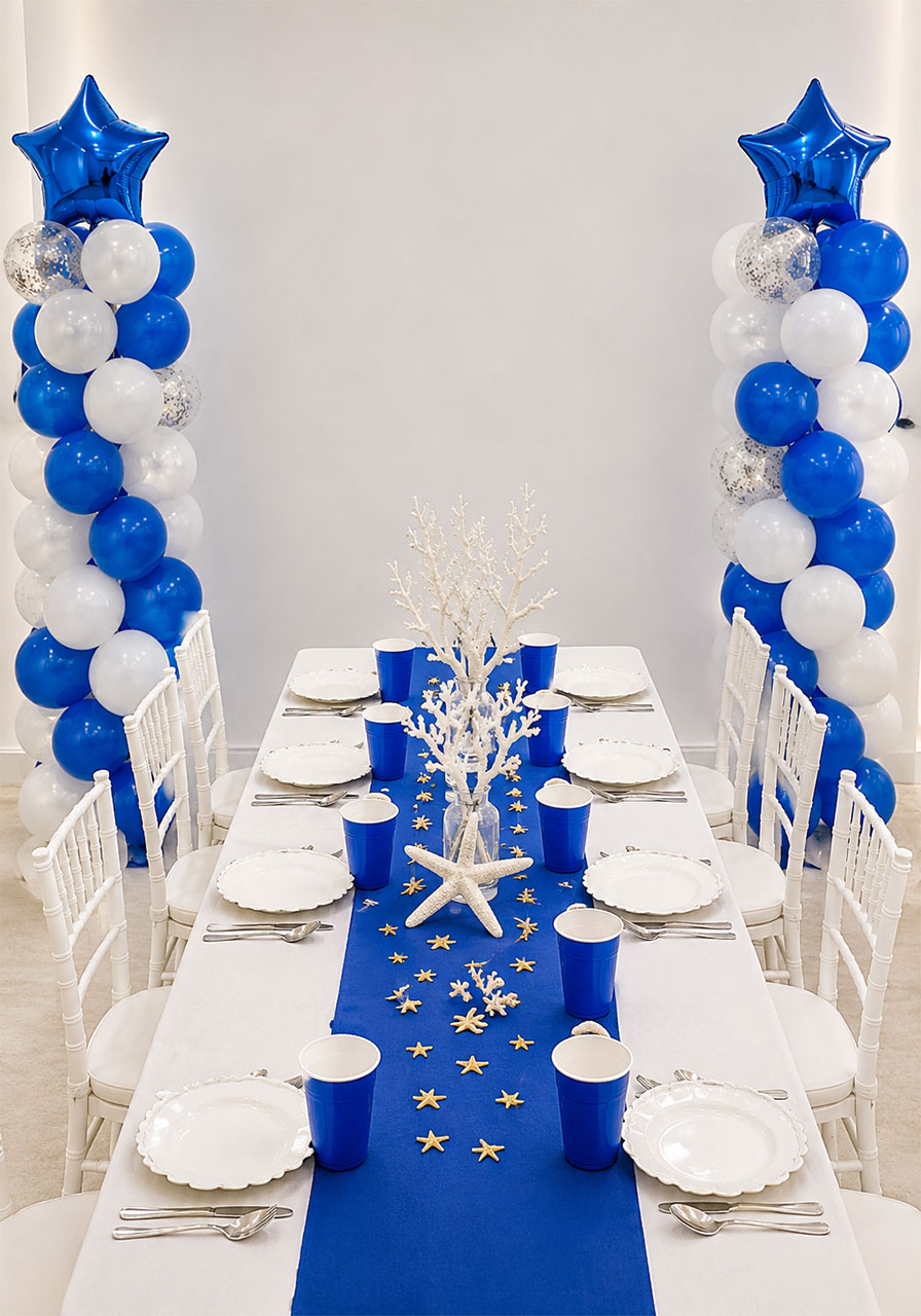 Classic blue and white under the sea birthday party table setup with balloon columns and coral centerpieces