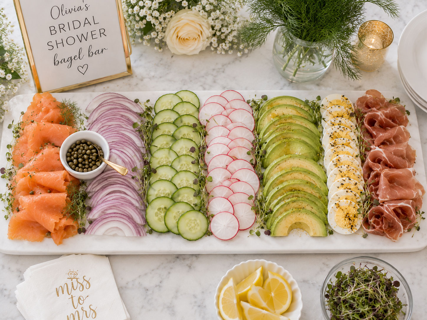 Savory toppings board with smoked salmon, capers, cucumbers, radishes, avocado, and prosciutto for a bridal shower bagel bar