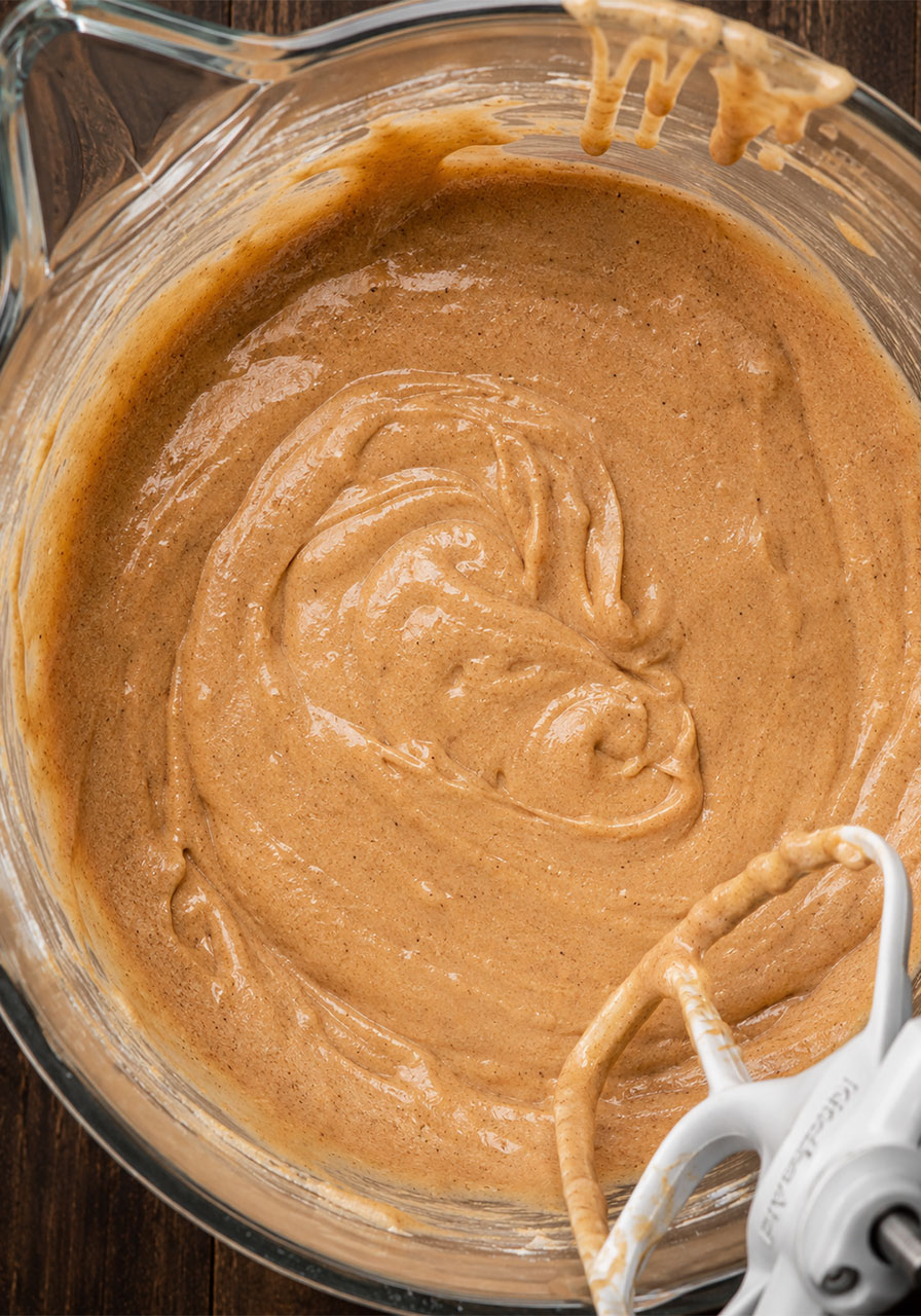 Smooth brown sugar chai cake batter with warm spice color in a stand mixer bowl ready to pour into pans
