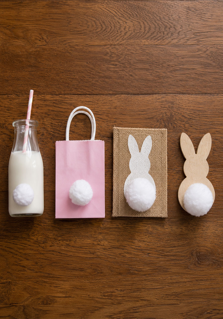 DIY cotton ball bunny tail decorations on milk bottles, favor bags, and burlap canvas for a bunny birthday party