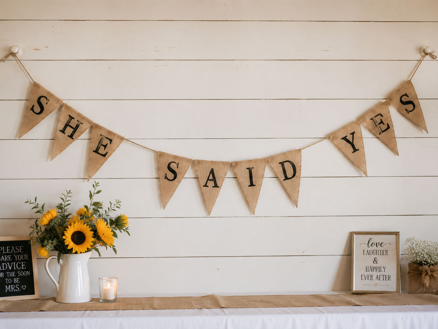 Rustic burlap pennant banner reading She Said Yes hung on white shiplap wall for bridal shower decor