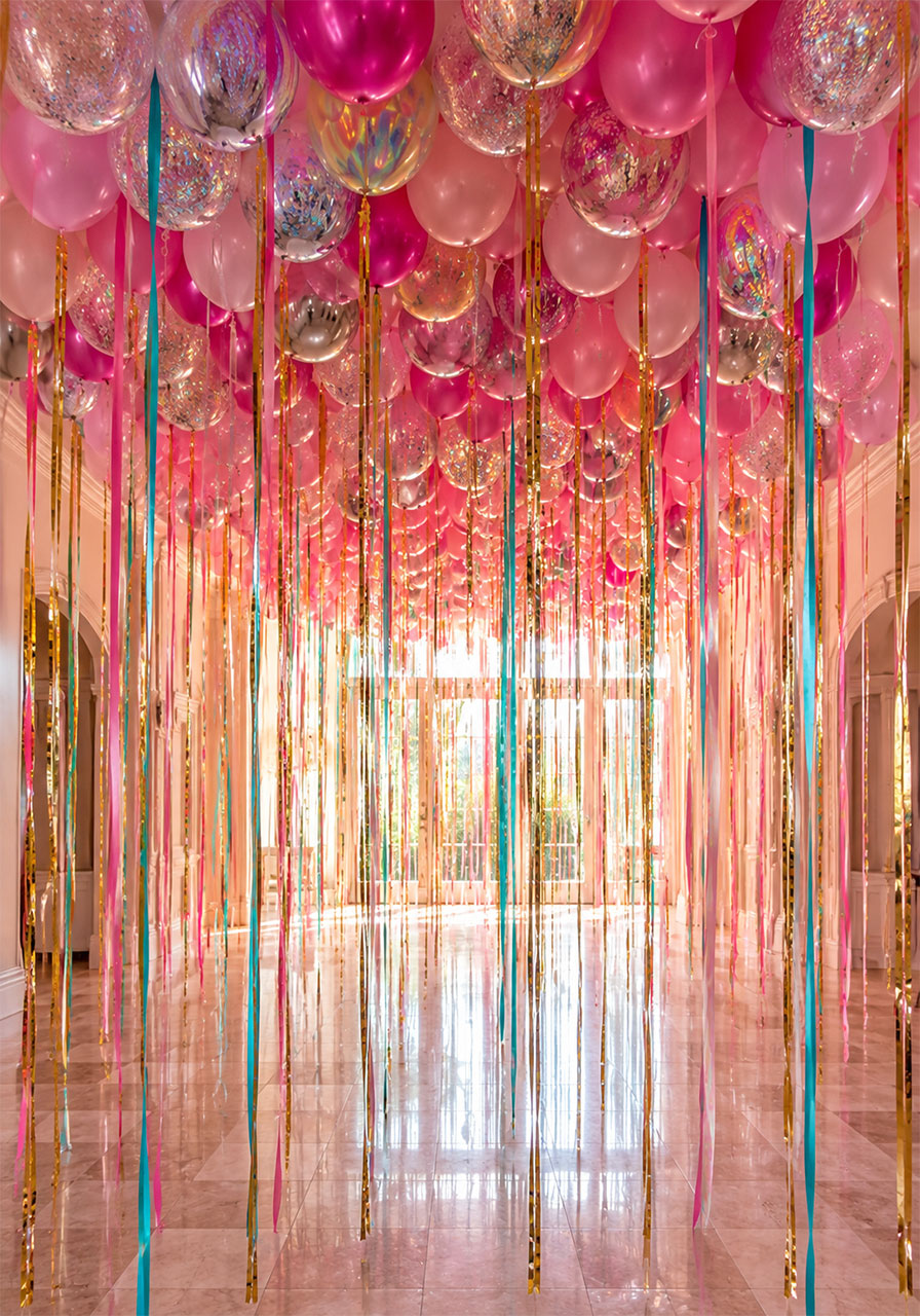 Ceiling covered in pink silver and confetti balloons with long flowing ribbon and tinsel curtain hanging down for a dramatic 10th birthday party entrance