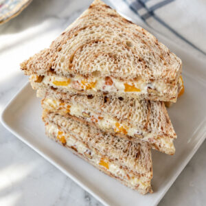 Stack of creamy orange cinnamon tea sandwiches with mandarin orange and pecan filling