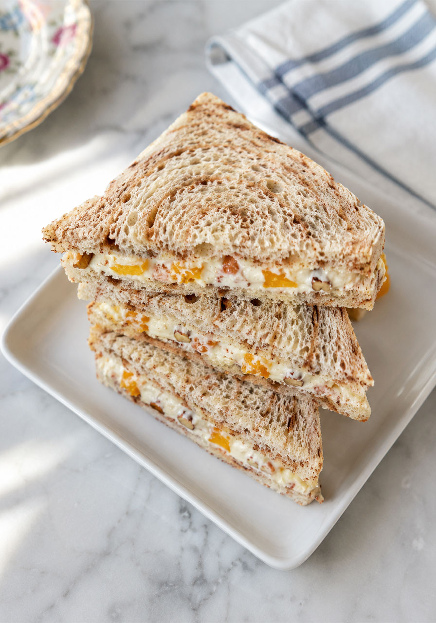 Stack of creamy orange cinnamon tea sandwiches with mandarin orange and pecan filling