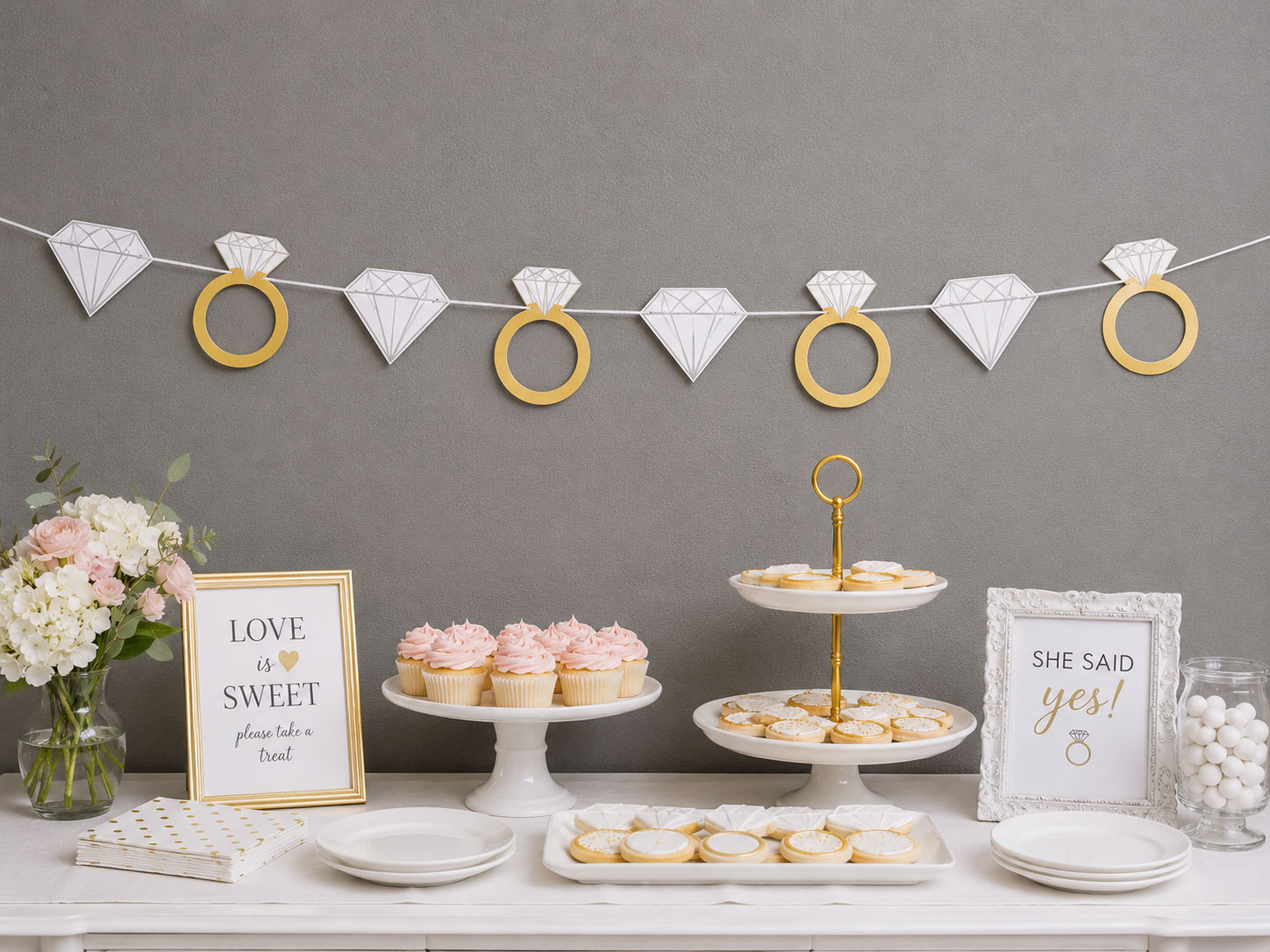 DIY diamond ring garland with white and gold cardstock shapes on twine above dessert table – bridal shower decoration idea