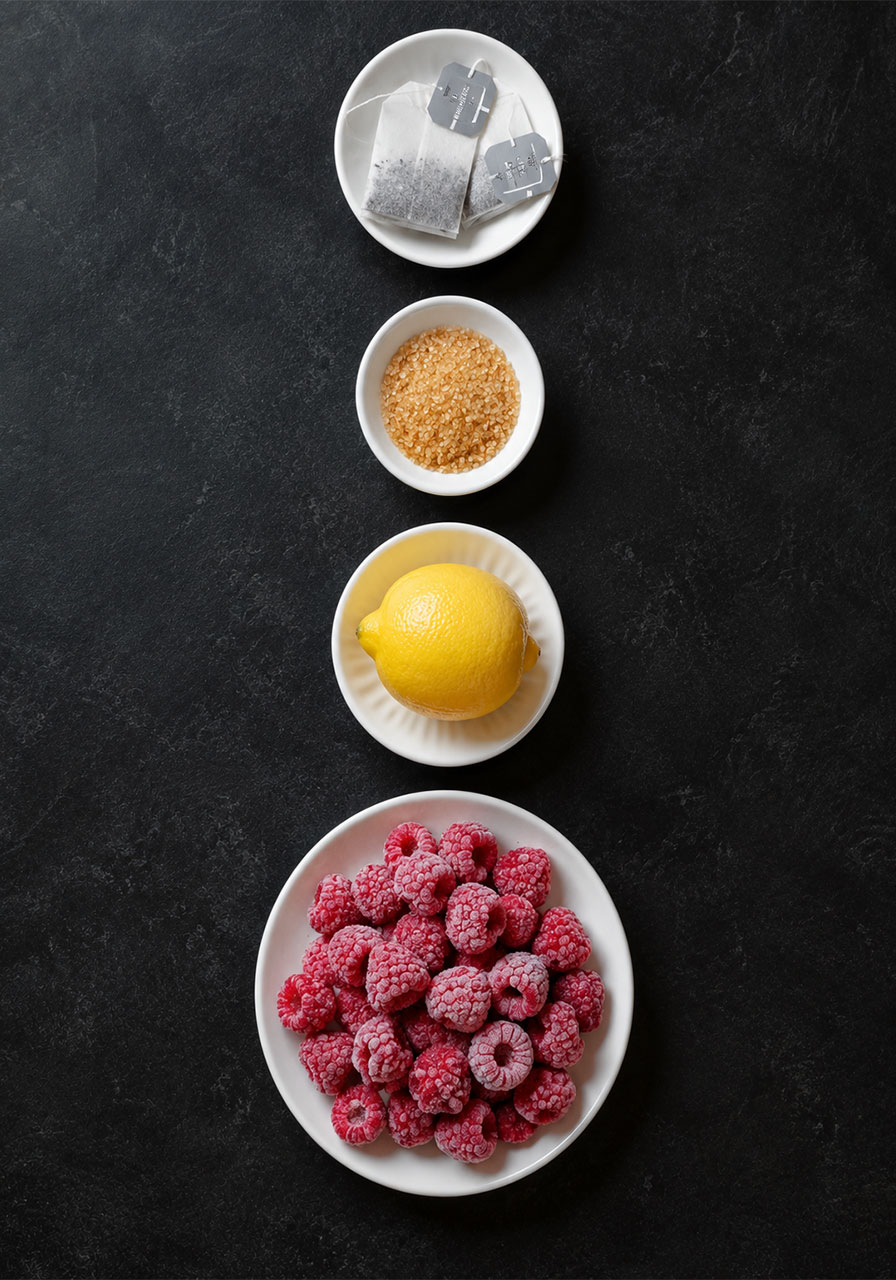 Ingredients for Earl Grey raspberry iced tea including tea bags, raspberries, lemon, and sugar