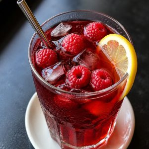 Glass of Earl Grey raspberry iced tea with fresh raspberries and lemon