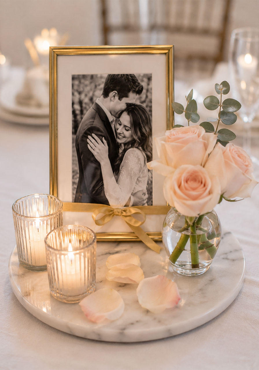 Framed engagement photo styled with fresh blush roses and votive candles on a marble tray as a personal bridal shower table centerpiece vignette
