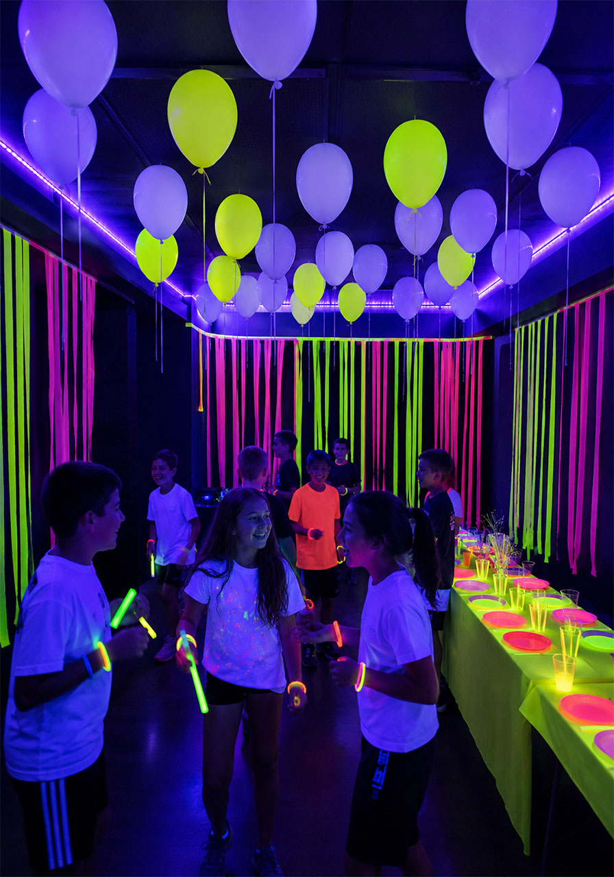 Glow in the dark neon blacklight party zone with UV balloons glowing streamers and kids wearing glow bracelets for an epic 10th birthday celebration