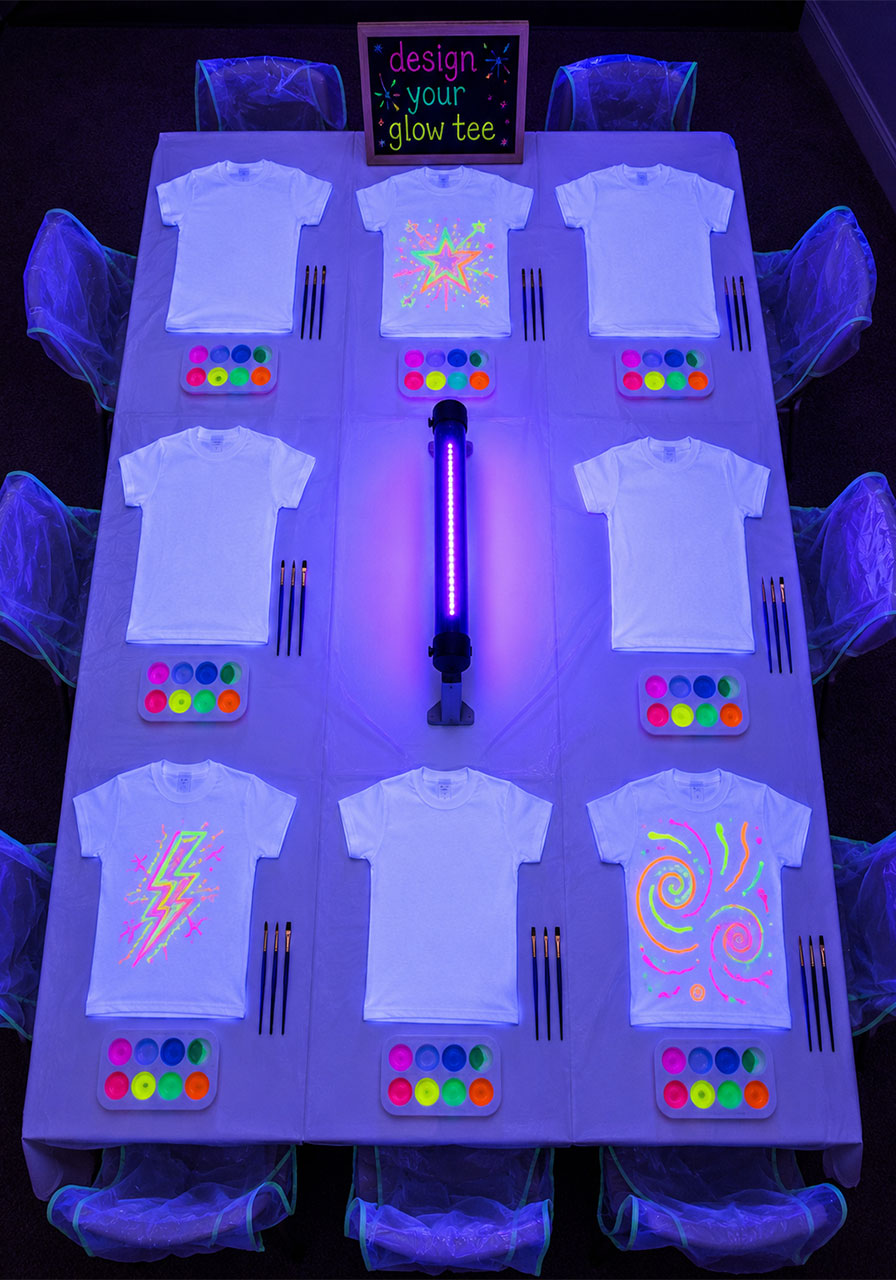 Glow-in-the-dark T-shirt painting craft station at a birthday party with UV-reactive neon paint under blacklight