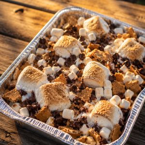 Grilled s'mores nachos recipe in a foil pan with melted chocolate and toasted marshmallows