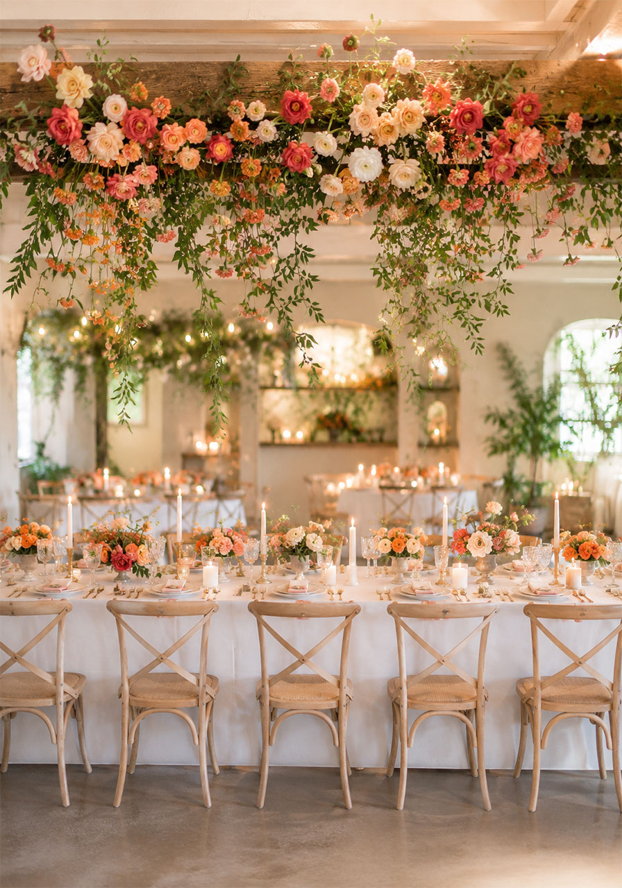 Lush orange carnation and rose hanging floral garland above a romantic indoor garden bridal shower dining table