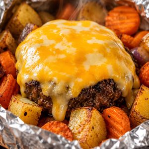 Melted Colby Jack cheese draped over a cooked beef patty inside an open campfire hobo packet