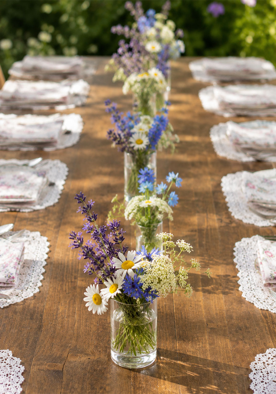 Tiny glass bud vases filled with wildflowers lining a tea party table