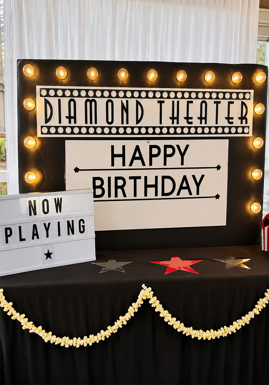 DIY movie theater marquee sign with Edison bulb lights and Art Deco lettering for a movie theater birthday party