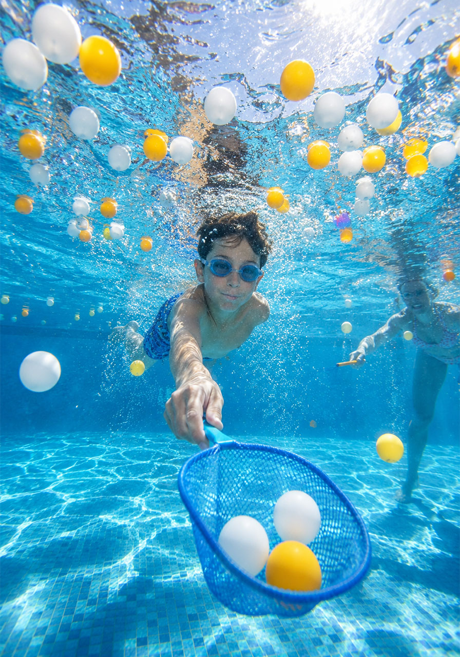 Kids scooping ping pong balls with nets underwater in ping pong ball scoop pool party game