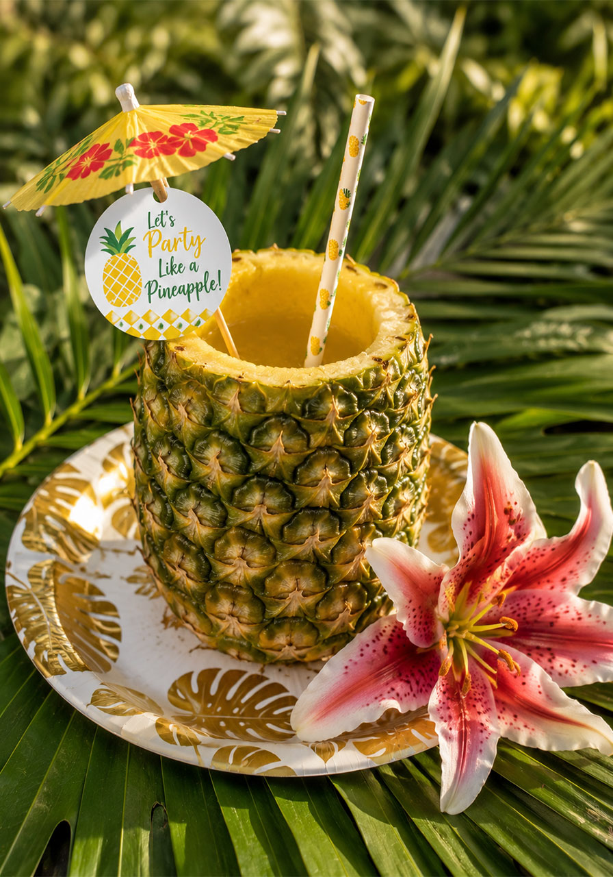 Hollowed real pineapple used as a tropical drink cup with paper straw and cocktail umbrella for birthday party snack bar
