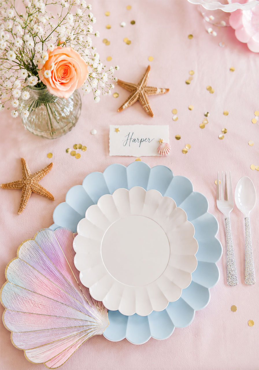 Scalloped blue and white plate setting with starfish accents for an under the sea birthday party tablescape