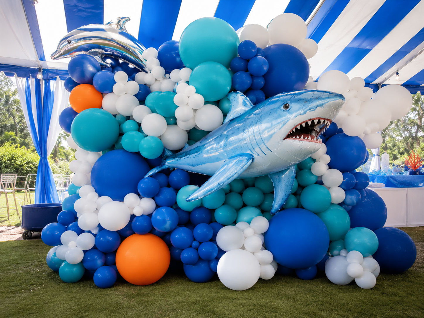 Giant shark foil balloon swimming through blue and teal balloon cluster for an under the sea birthday party