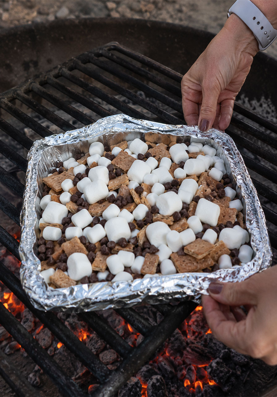 Covering s'mores nachos foil pan with aluminum foil before grilling