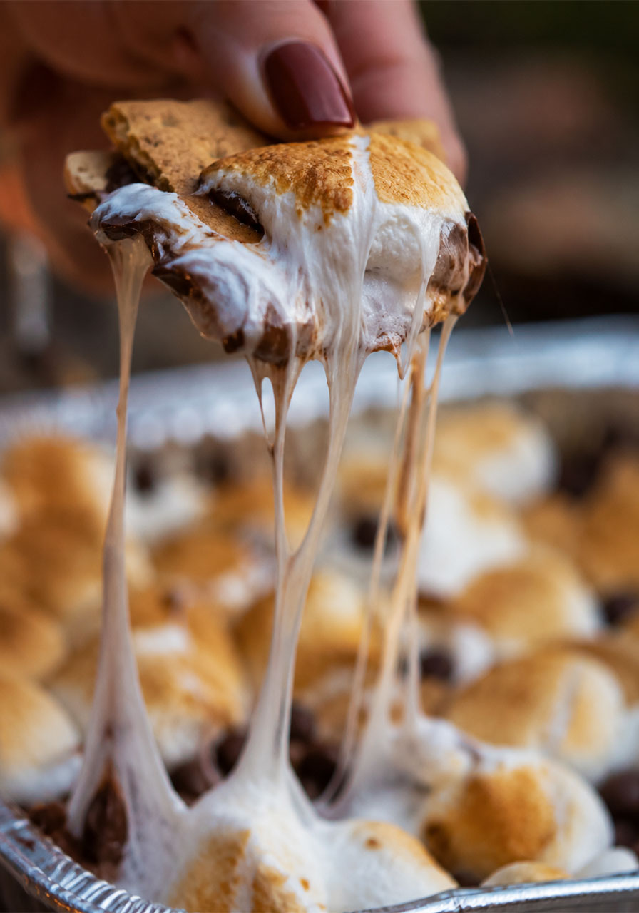 Close up of gooey melted marshmallow and chocolate being pulled from s'mores nachos