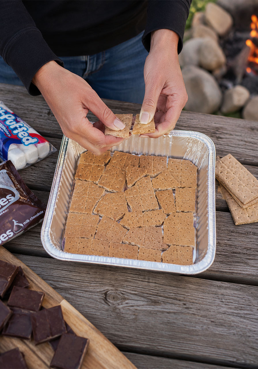 Step 1 of making s'mores nachos, layering graham crackers in a foil pan
