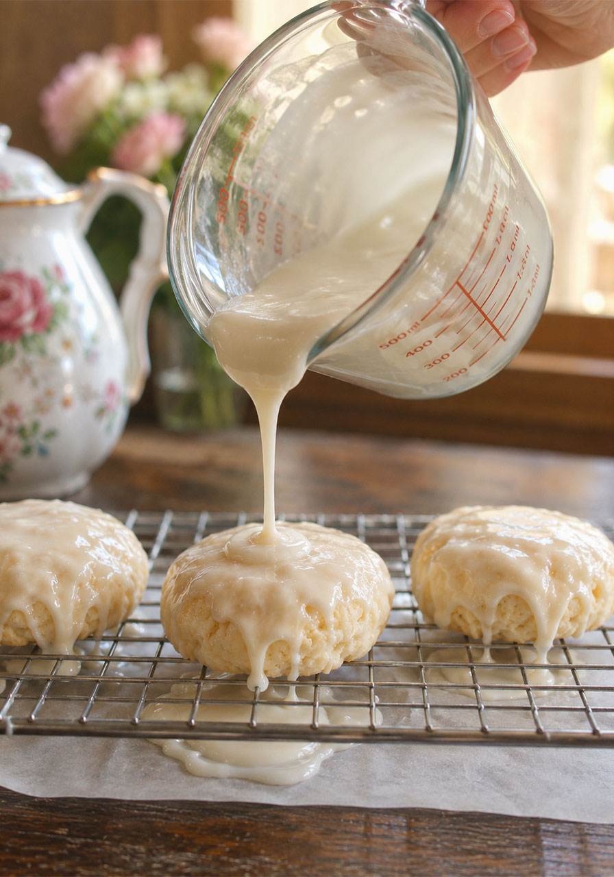 Pouring almond vanilla glaze over warm Southern tea cakes