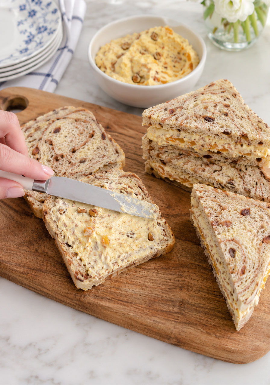 Spreading creamy orange filling on cinnamon swirl bread and cutting into triangle tea sandwiches