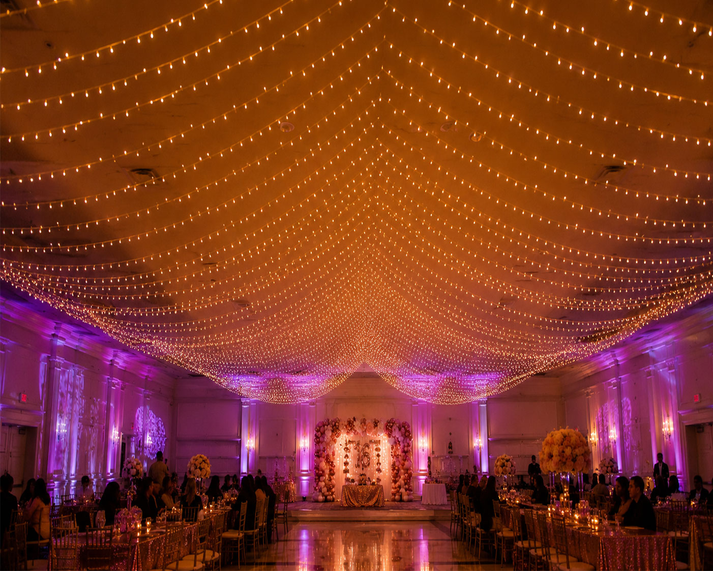String light canopy ceiling with warm Edison bulbs creating a romantic atmosphere at a rose gold Sweet 16 party venue
