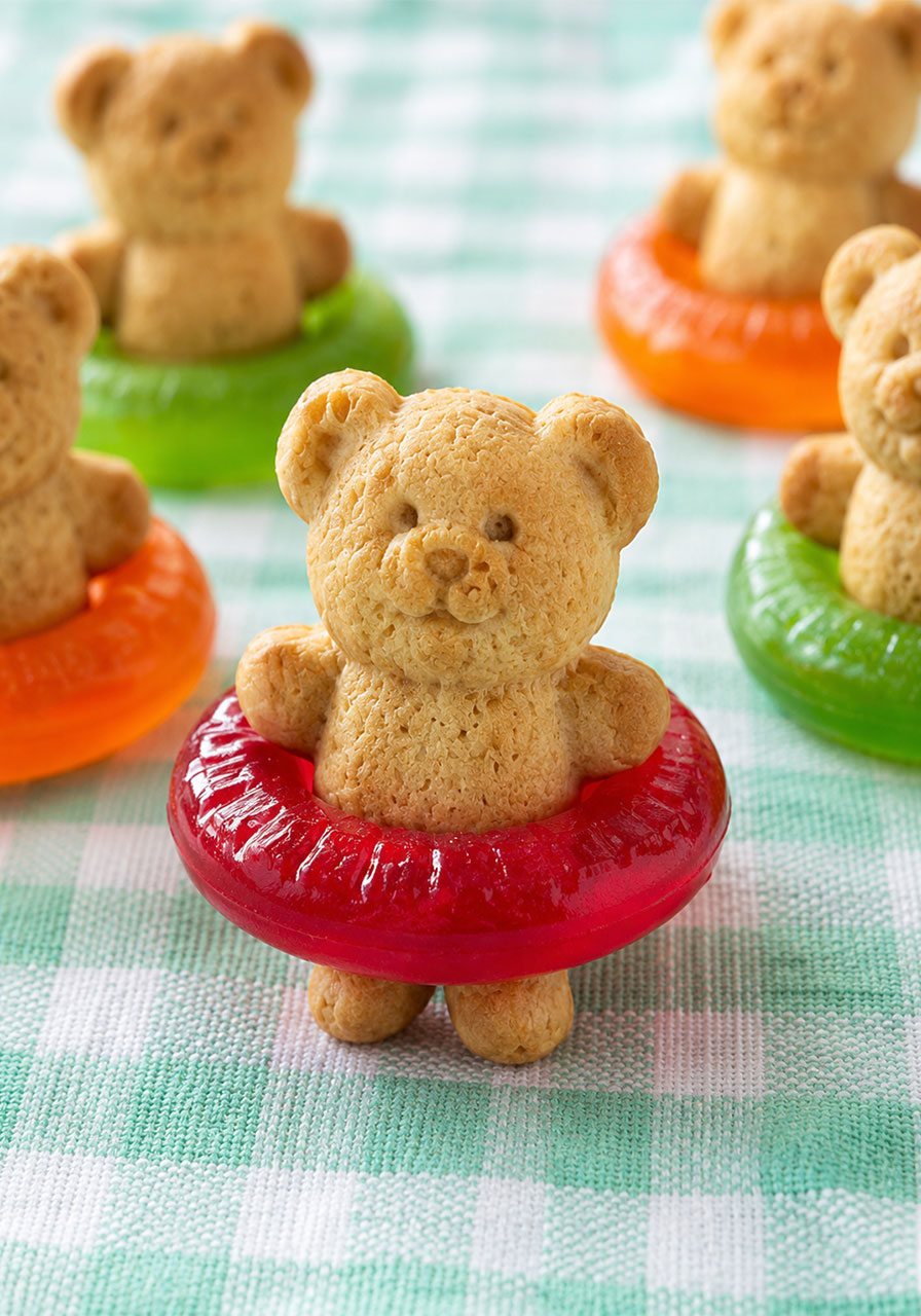 Teddy Graham cracker sitting inside a red gummy Lifesaver candy ring like a swimmer in an inner tube – adorable pool party Jello cup decoration step
