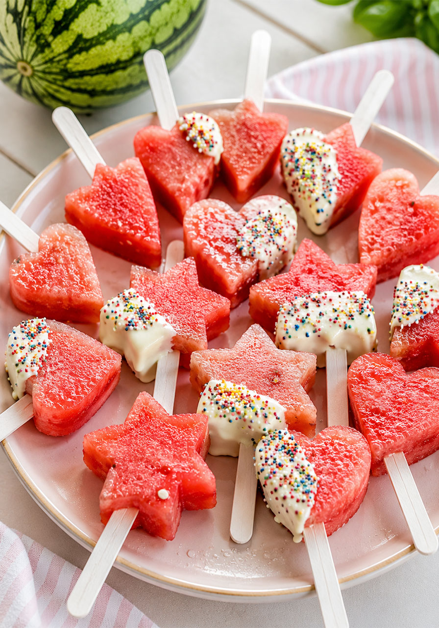 Star-shaped watermelon popsicles on sticks with white chocolate and sprinkles for summer party dessert