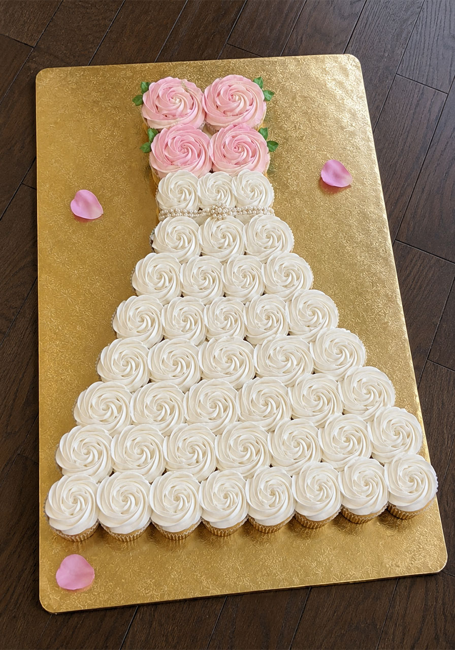 Wedding dress cupcake cake with white and pink buttercream rosettes on gold board – showstopper bridal shower dessert idea