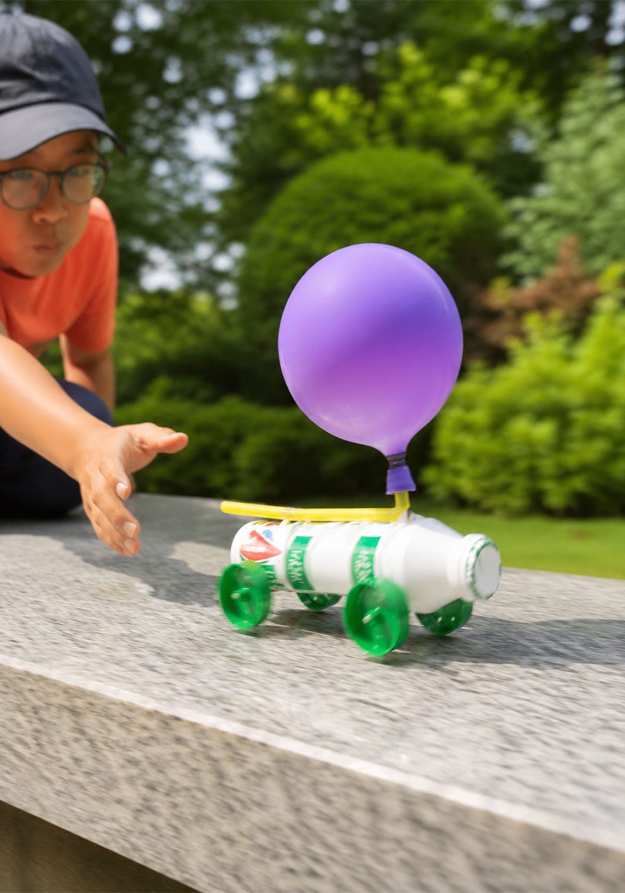 Balloon-powered recycled car racing forward during a STEM activity demonstration