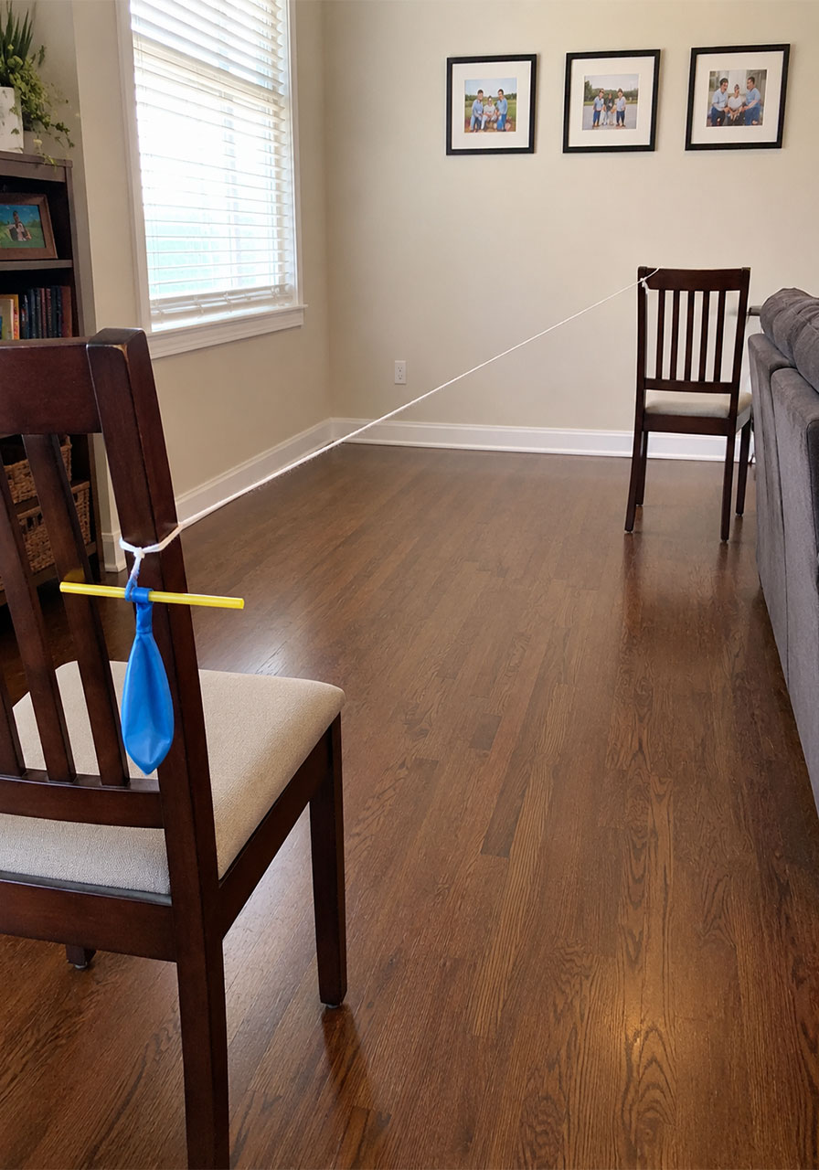 Indoor string setup for a balloon rocket experiment stretched between two chairs