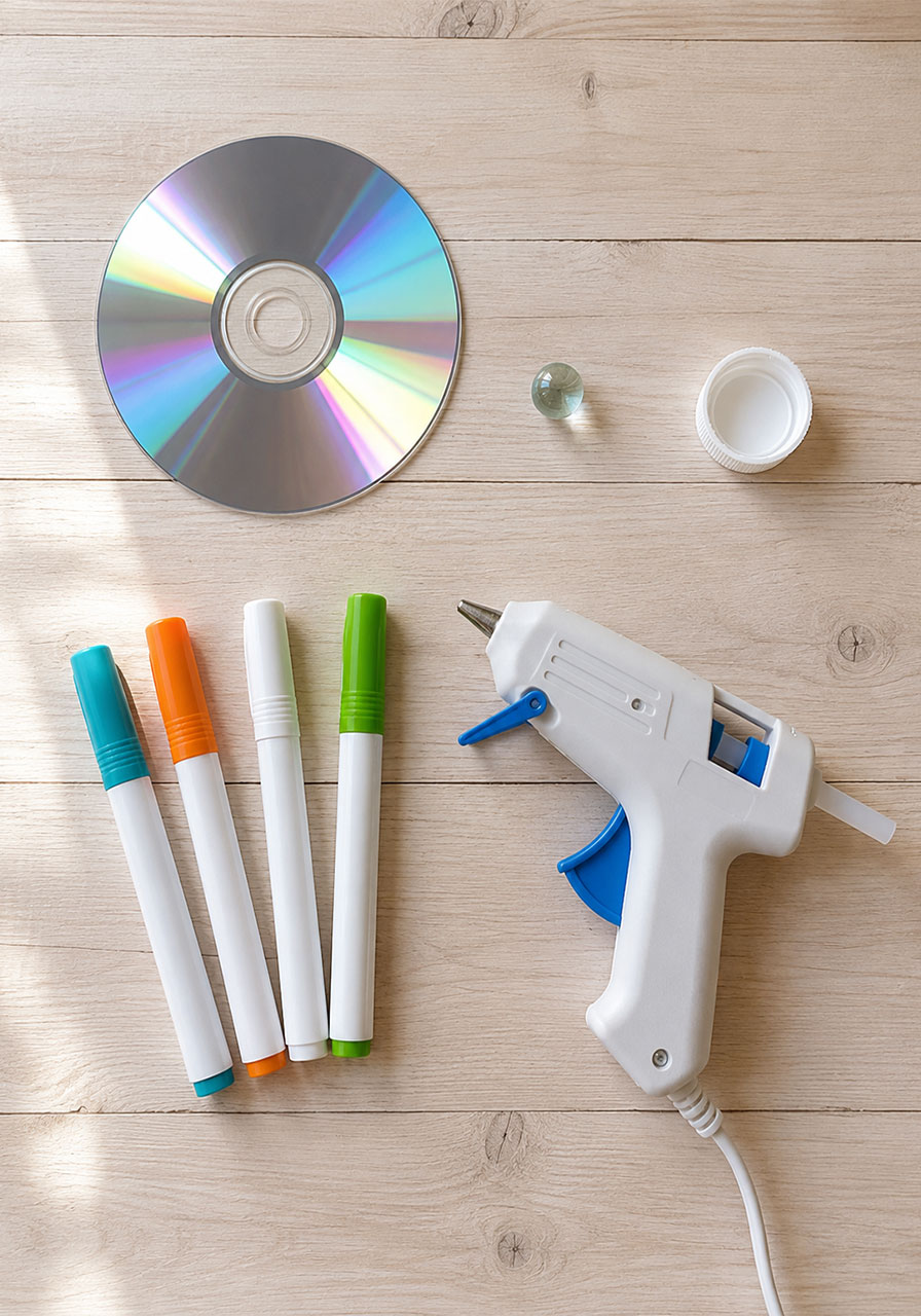 Materials needed for CD spinning top craft: CD, marble, bottle cap, hot glue gun, and chalk markers