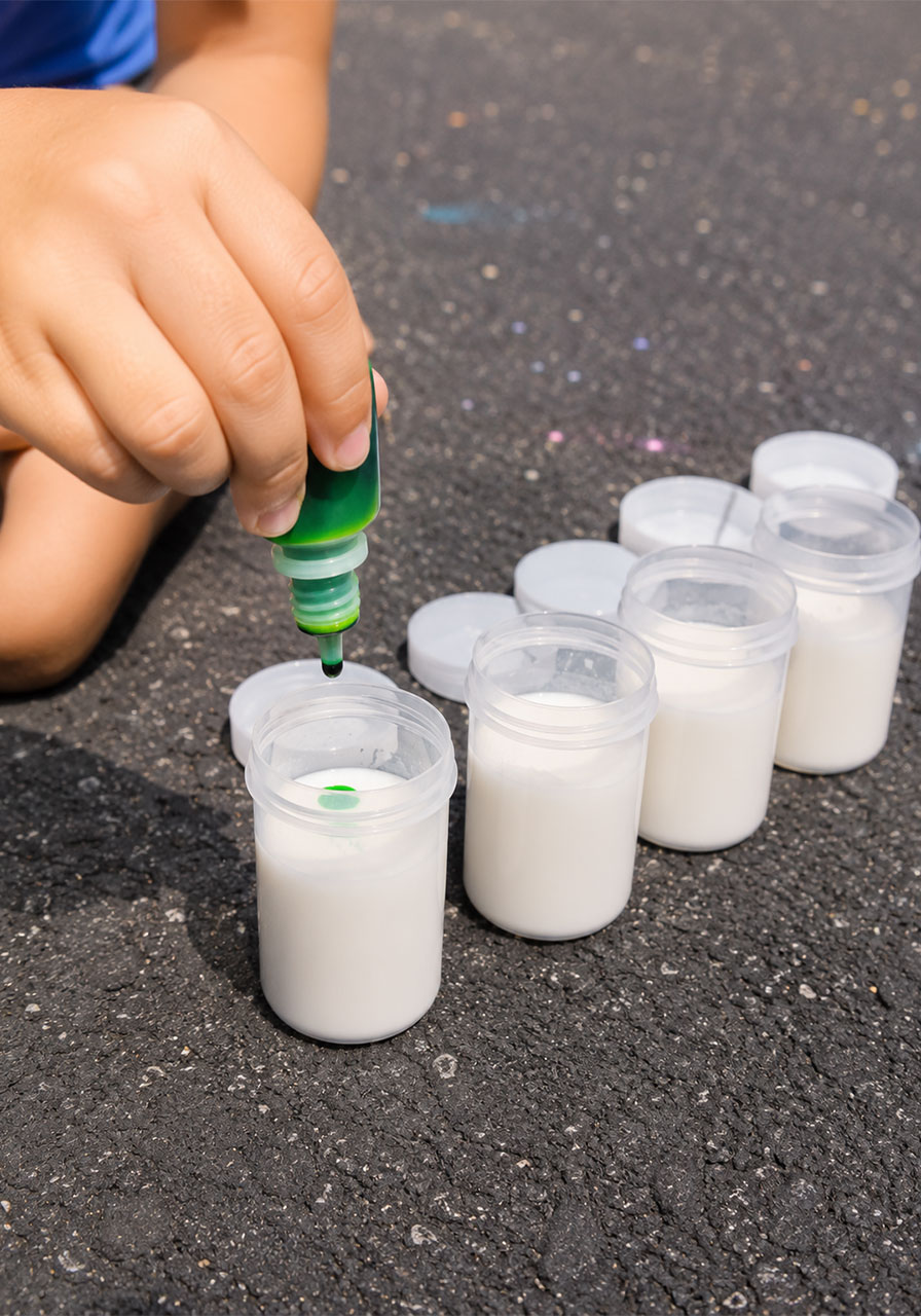 Adding food coloring to chalk rocket mixture in plastic canisters