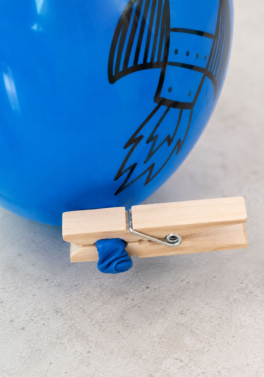 Using a clothespin to hold a balloon closed before launching a balloon rocket