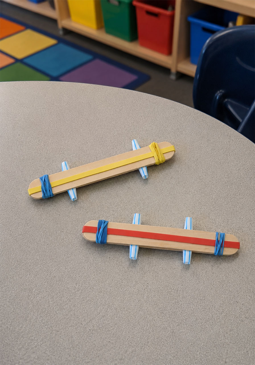 Securing the craft sticks together with a rubber band to build the harmonica