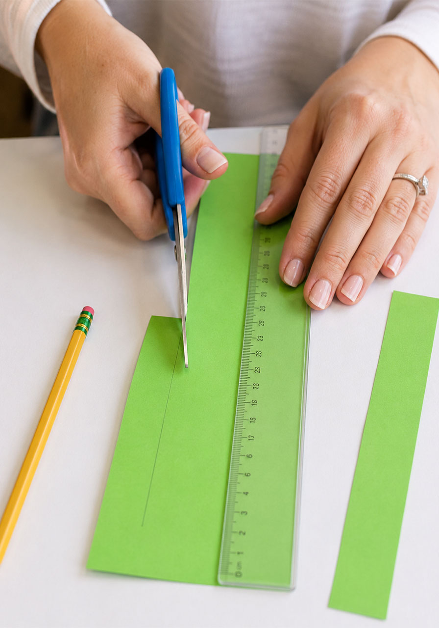 Cutting a measured paper strip to make the loops for a hoop glider paper airplane