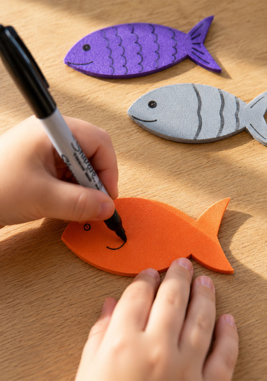 Drawing face and scale details on craft foam fish before swimming experiment