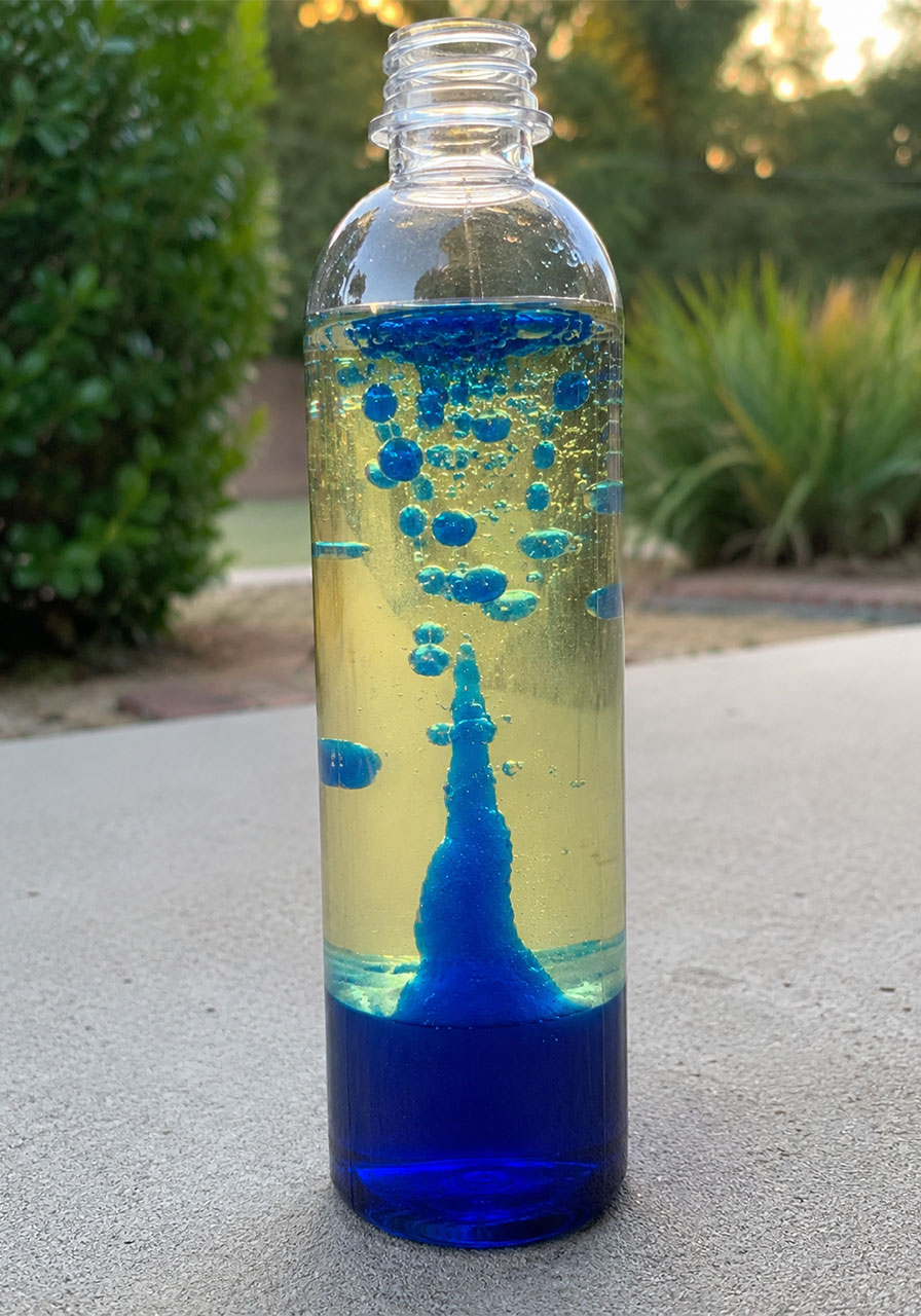 Homemade DIY lava lamp glowing blue bubbles rising through oil and water