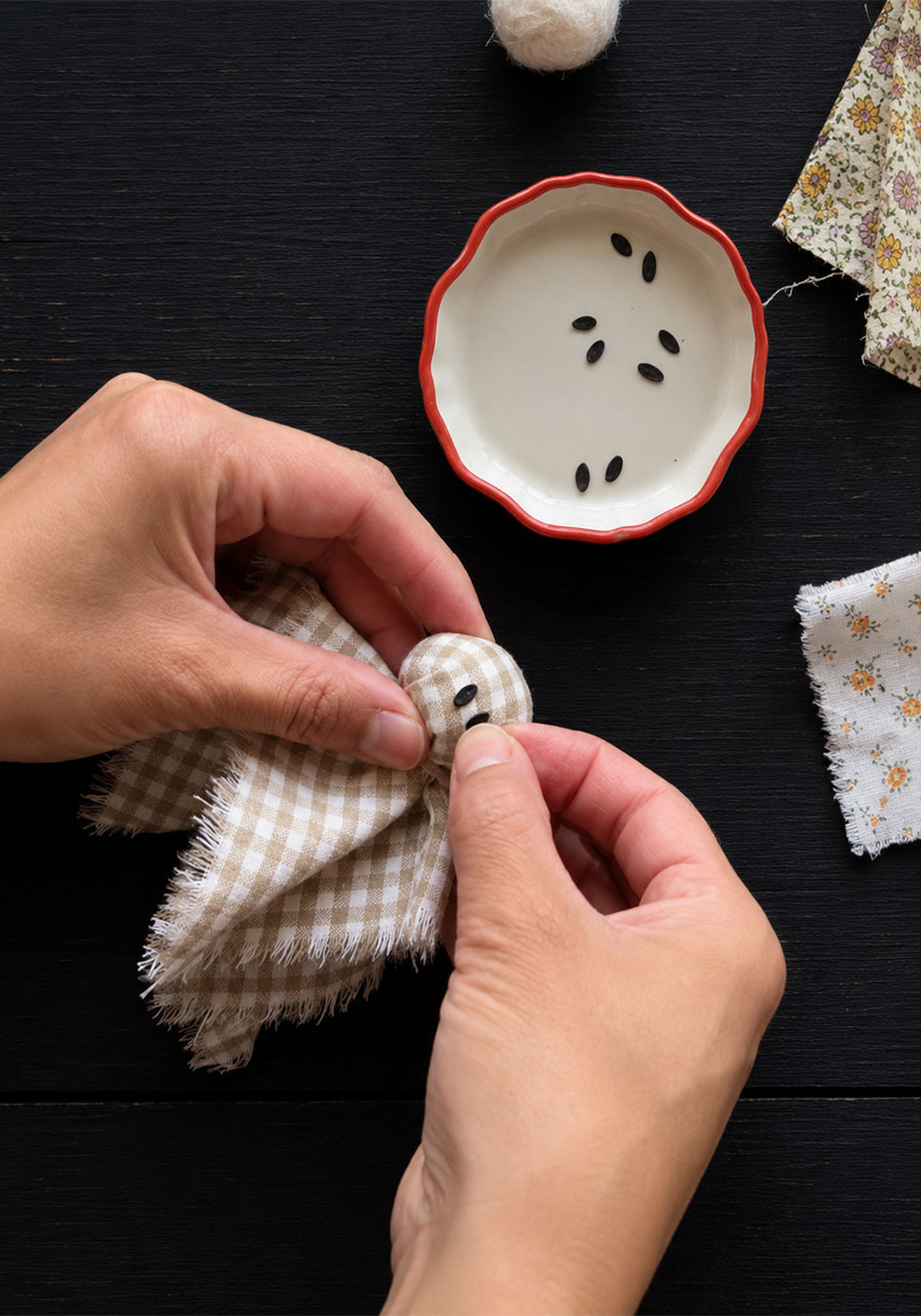 Drawing small black dot eyes onto a felted fabric ghost head