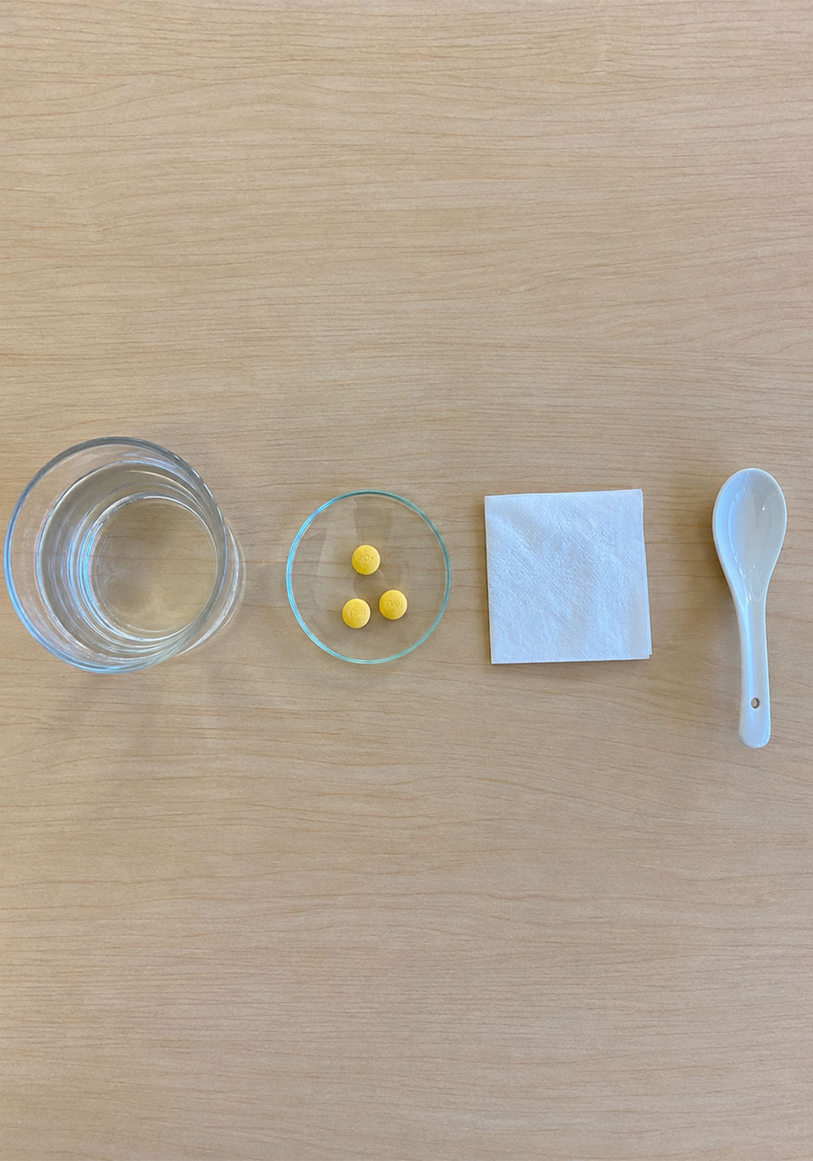 Materials needed for the fluorescent meteor shower STEM experiment: glass of water, vitamin B tablets, tissue paper, and spoon