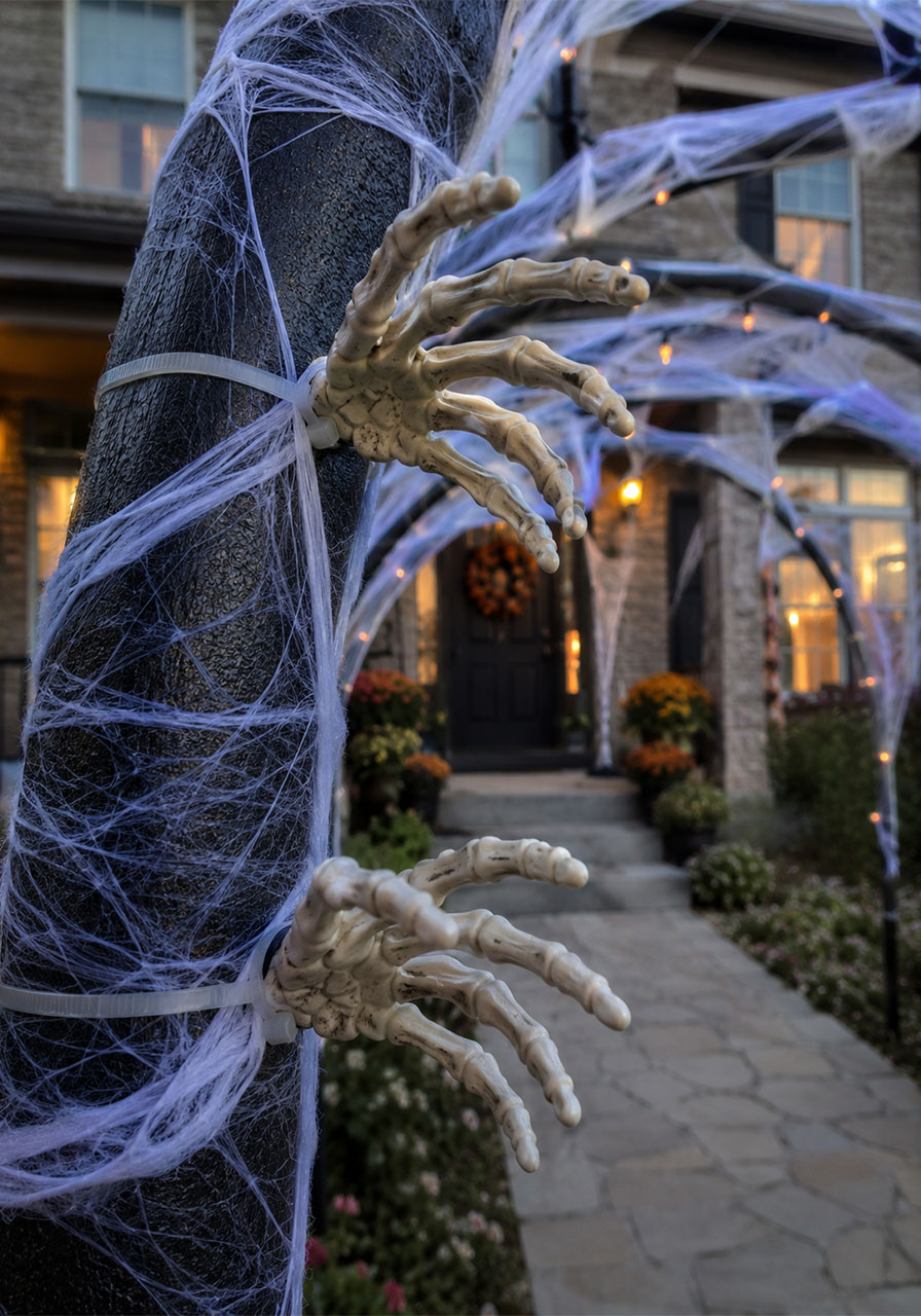 Skeleton hands reaching through spider webbing on a Halloween archway