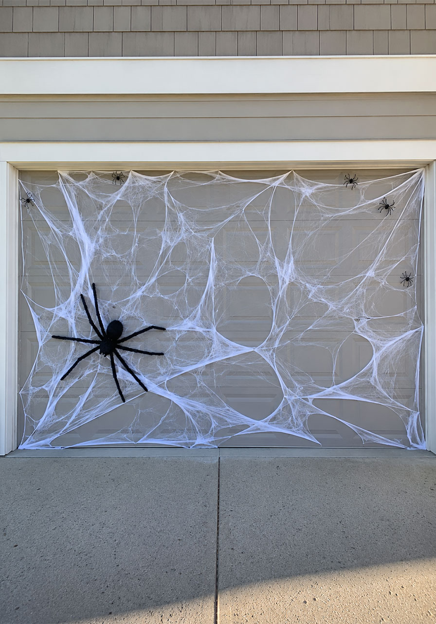Giant stretched spider web with a large fake spider covering a Halloween garage door