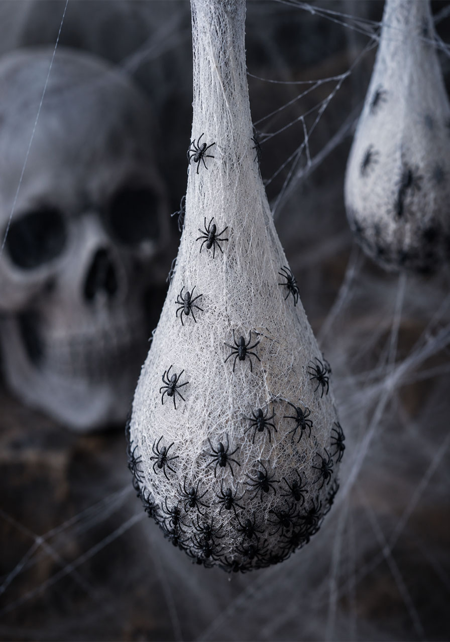 Creepy pantyhose spider egg nests covered in plastic spiders for Halloween porch decor