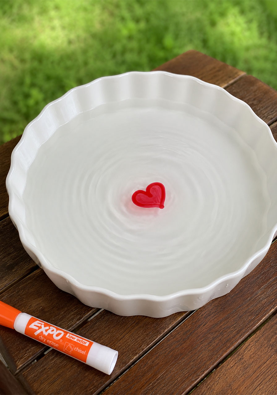Red heart drawing floating on water in a dish, dry erase floating ink experiment